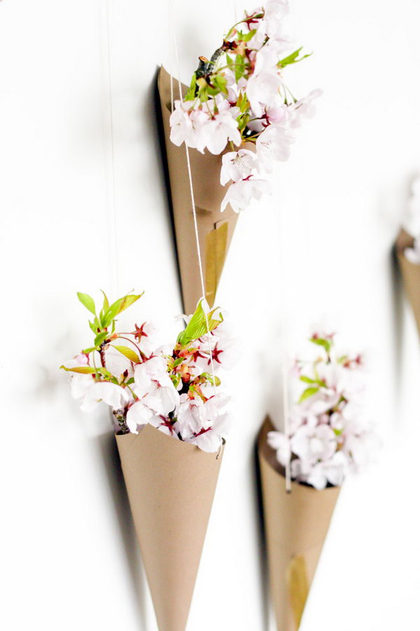 Blooming flower cone wall display. Create cones out of cardboard, punch 2 holes on both sides and take the cord to hang the cone upside down. Arrange the cones on the wall and place some flowers in them to create the beautiful wall art for your dormitory.