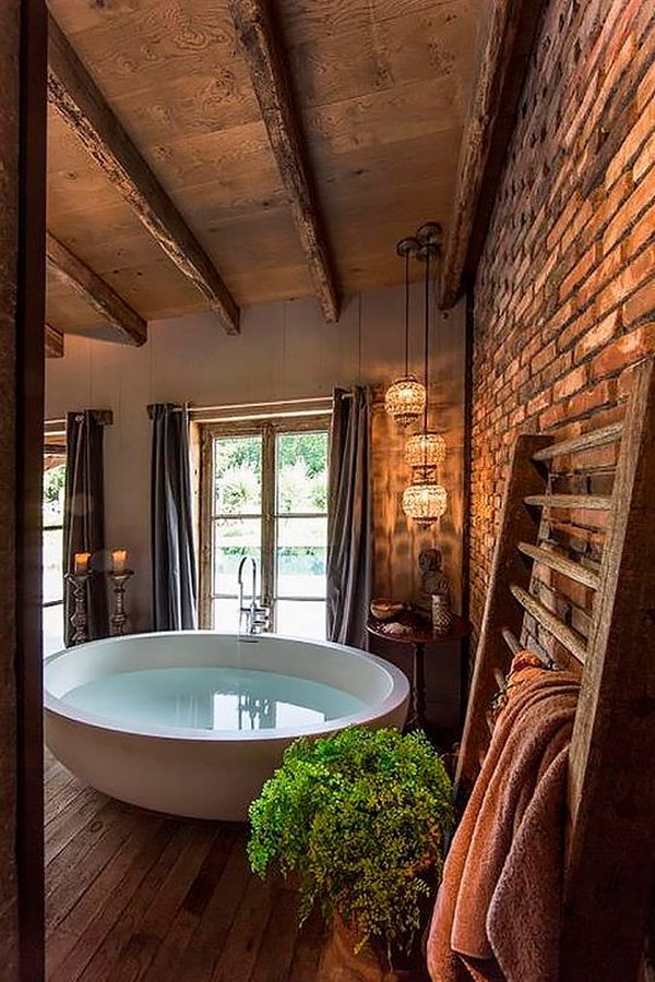     Barn wood floor and ceiling, exposed brick wall, round bathtub in a large rustic bathroom 