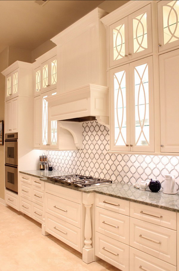 Stunning Calcutta gold marble and gray glass backsplash with beautiful white cabinets 