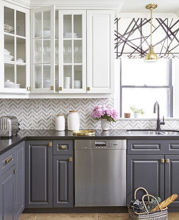 Gray and white chevron tile backsplash in a stylish kitchen with contrasting cabinets 