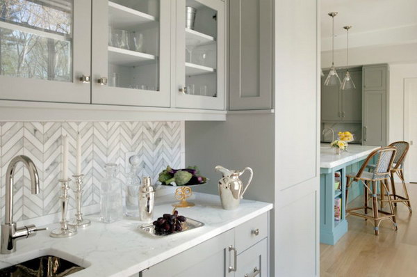 Chevron backsplash with marble tiles and light gray furniture 
