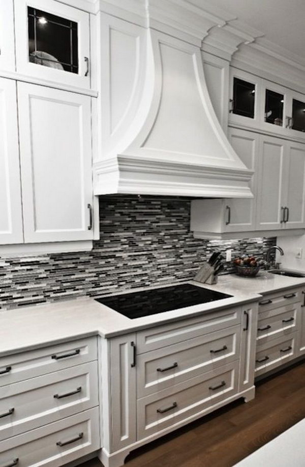 Black or gray linear glass tile backsplash with white cabinets and marble countertops  