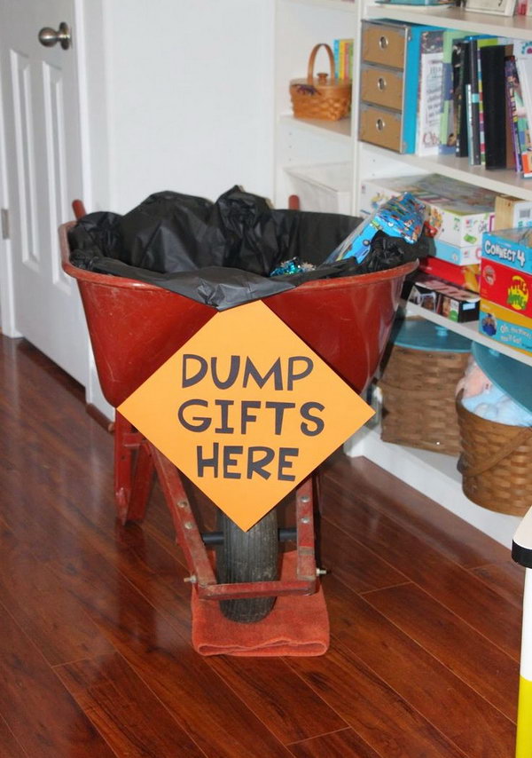     Construction birthday party decoration: add a black tablecloth for the decoration and my funny dump gifts sign here to a wheelbarrow and put all the gifts for the decoration in it.  