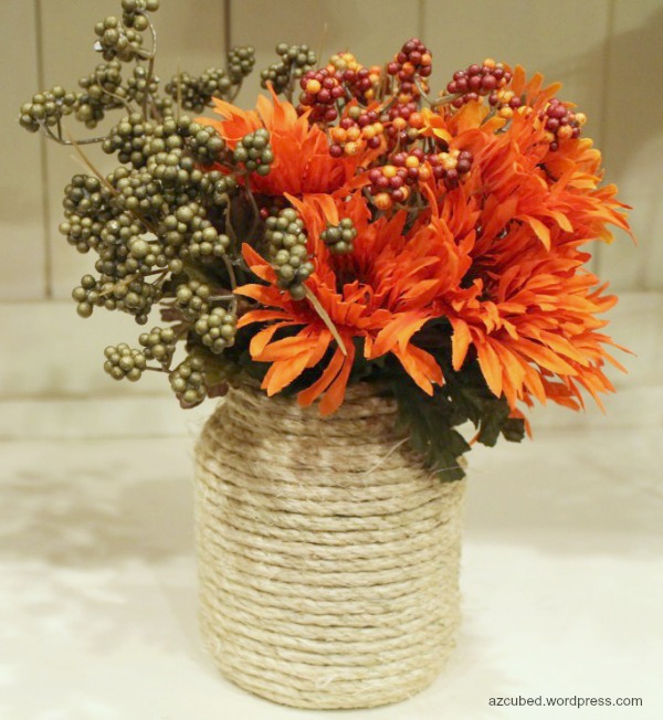 DIY rope wrapped in vase. A vase, a few ropes, a hot glue gun, and hot glue are all you need to make this rope-wrapped vase. It will be an amazing table centerpiece with some autumn flowers and leaves.