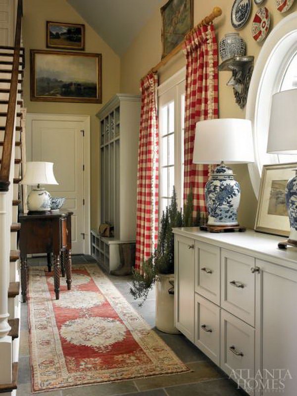     Farmhouse mud room. Classic blue and white relics like other traditional decors such as an oushak carpet, a mahogany buffet and red and white checked curtains. 