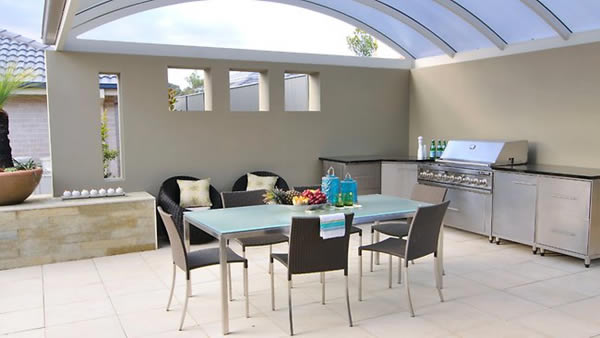 This is a typical modern outdoor kitchen with the glass roof and the gray, white and black elements. 