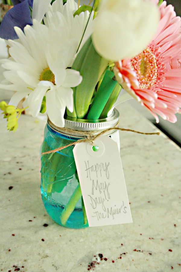 Flower jar for May. Take a ribbon and tie a small label. Fill your mason jars with water and arrange flowers as you wish. Place the screw strap on the glass. You will receive this artistic flower jar for May in a beautiful design.