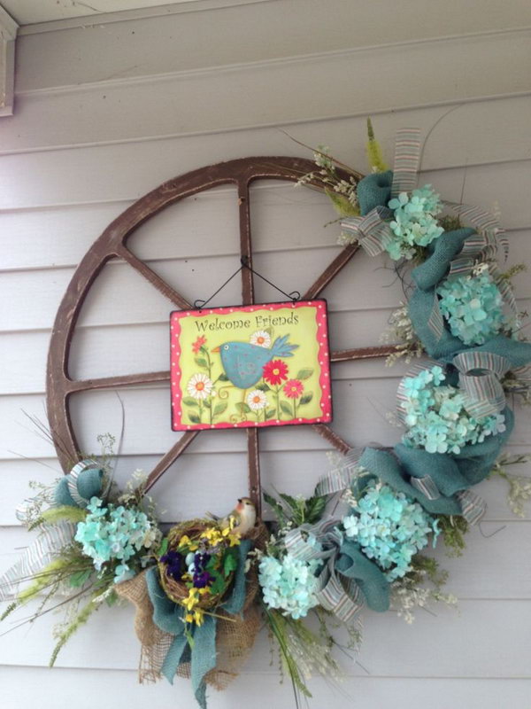 Easter decorated wheel rim. Wreath becomes a traditional way for Easter decoration with Easter egg, fresh flowers, Easter bunny elements. What distinguishes this from other wreaths is the wheel decorated with flowers. A picture hangs in the middle.