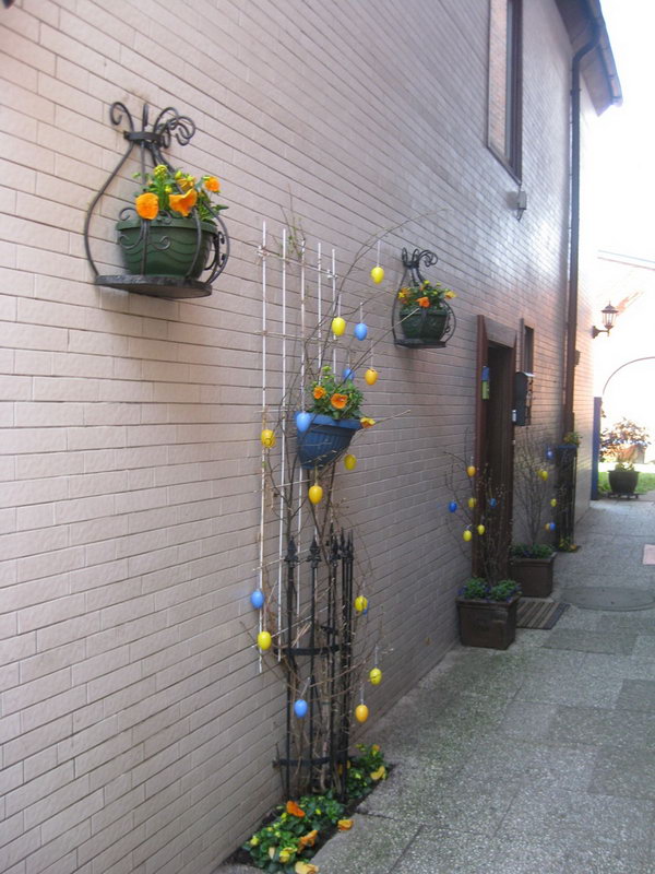 Easter garden decoration. Attach the flower pot to the iron railing and cover some branches, hang yellow and blue Easter eggs on all branches. You will receive this beautiful garden design Easter decoration.