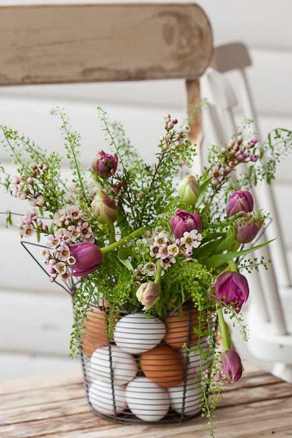 Easter centerpiece with eggs and flowers. Place the flowers in a vase in a wire basket and place plastic eggs in between. It is perfect for an elegant Easter table display. 