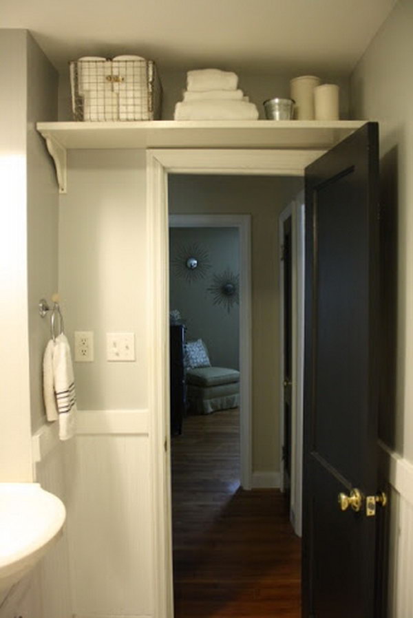 Store bathroom utensils such as toilet paper and additional towels on the shelf above the door. 