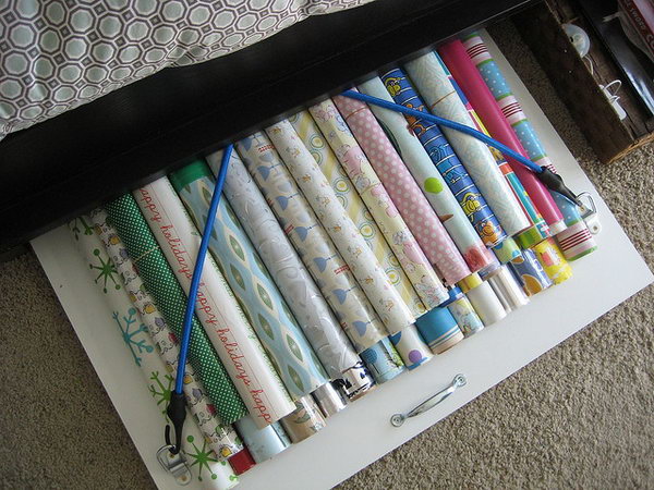 Organize your wrapping paper under the bed with a board with bungee cords. 