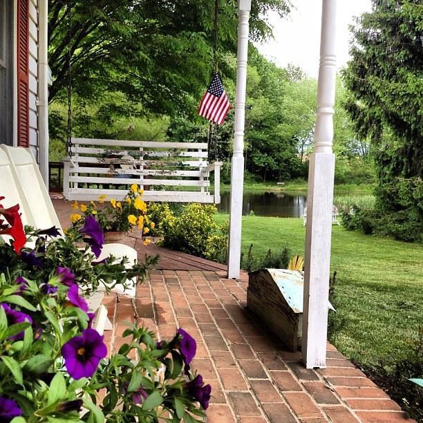 Vintage wooden porch swing and American flag at Pinky Swear Farm .