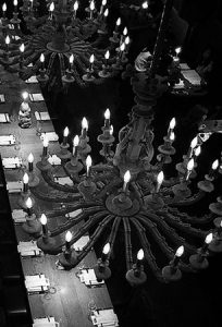 A row of 4 giant chandeliers hanging over the long shared banquet .