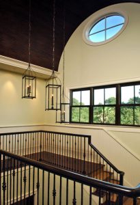 Trio of chandeliers at different heights adds interest to stairway .