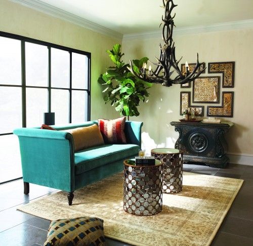 Soft turquoise velvet sofa, mirrored tables & antler chandelier .