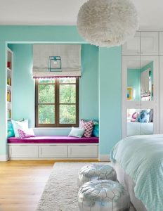 Turquoise blue girl's bedroom features a white feather chandelier .